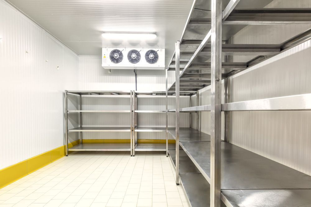 A room with stainless steel shelves and a refrigerator.