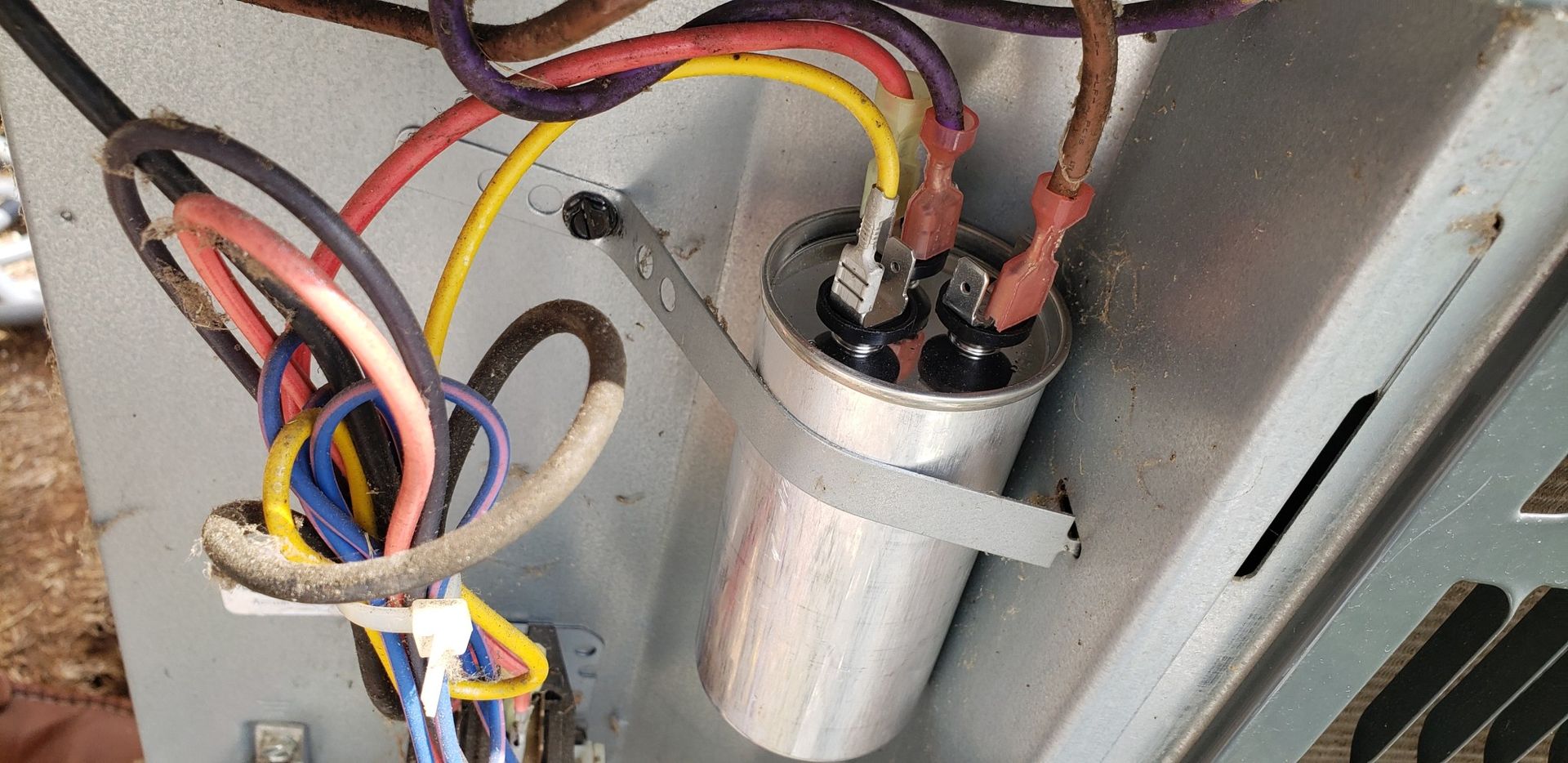 A close up of a capacitor with wires attached to it.