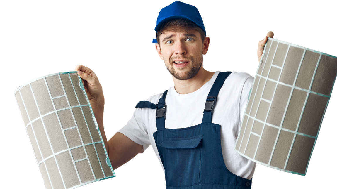 A man in overalls is holding two filters in his hands.