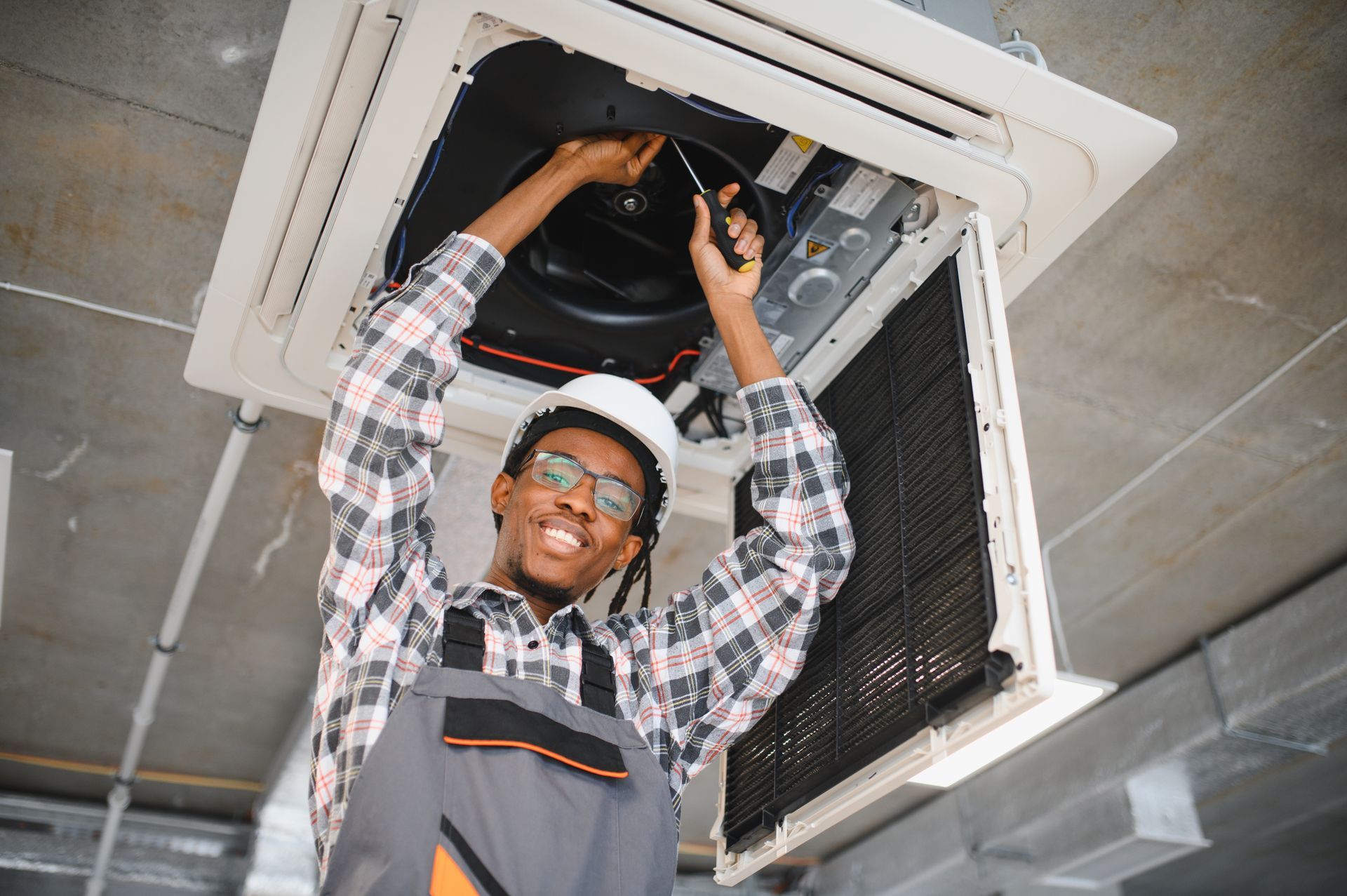 A man is working on an air conditioner in a building.