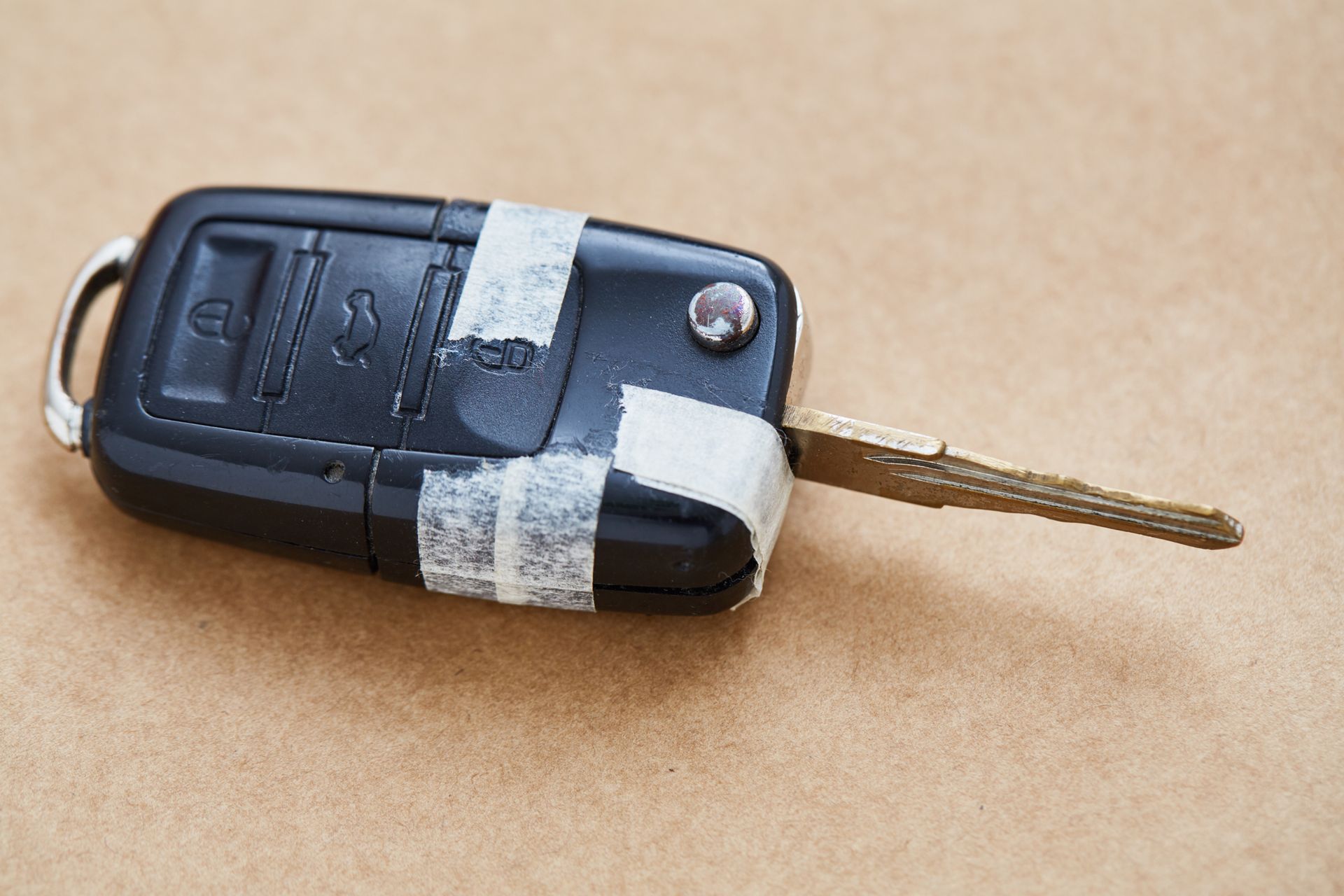 A car key is taped to a piece of tape on a table.