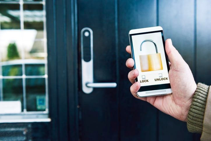 A person is holding a smart phone in front of a door.