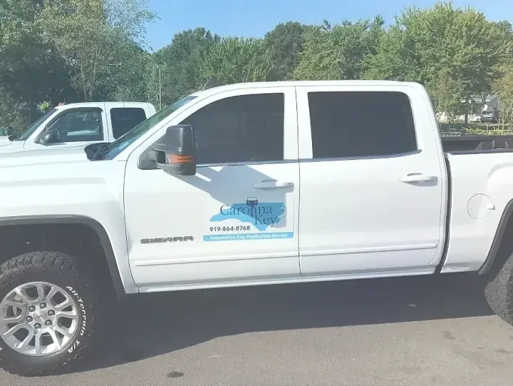 A white truck is parked in a parking lot with trees in the background.