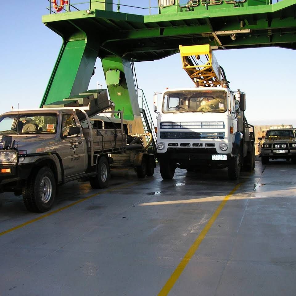 Vehicles on a Ferry, Under a Green Gantry — NRG Drilling in Tin Can Bay, QLD