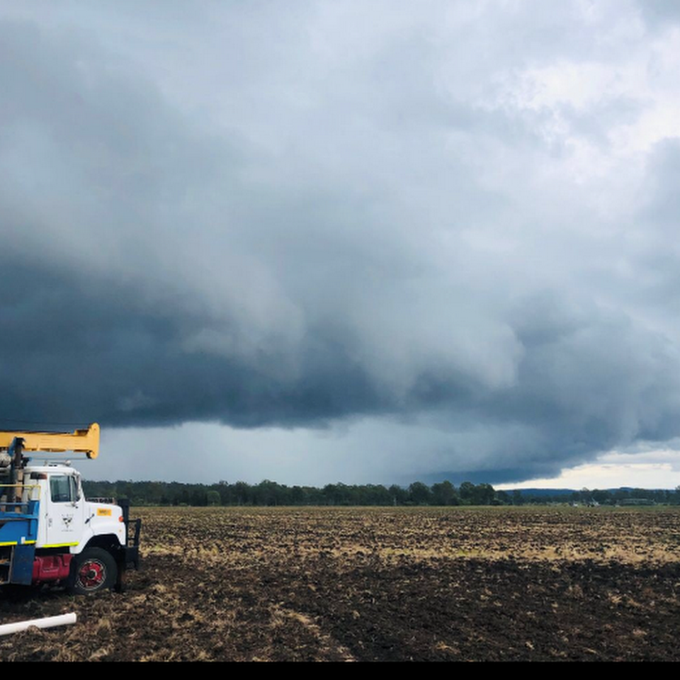 Storm Clouds Over a Field With a Utility Truck Parked — NRG Drilling in Cooroy, QLD