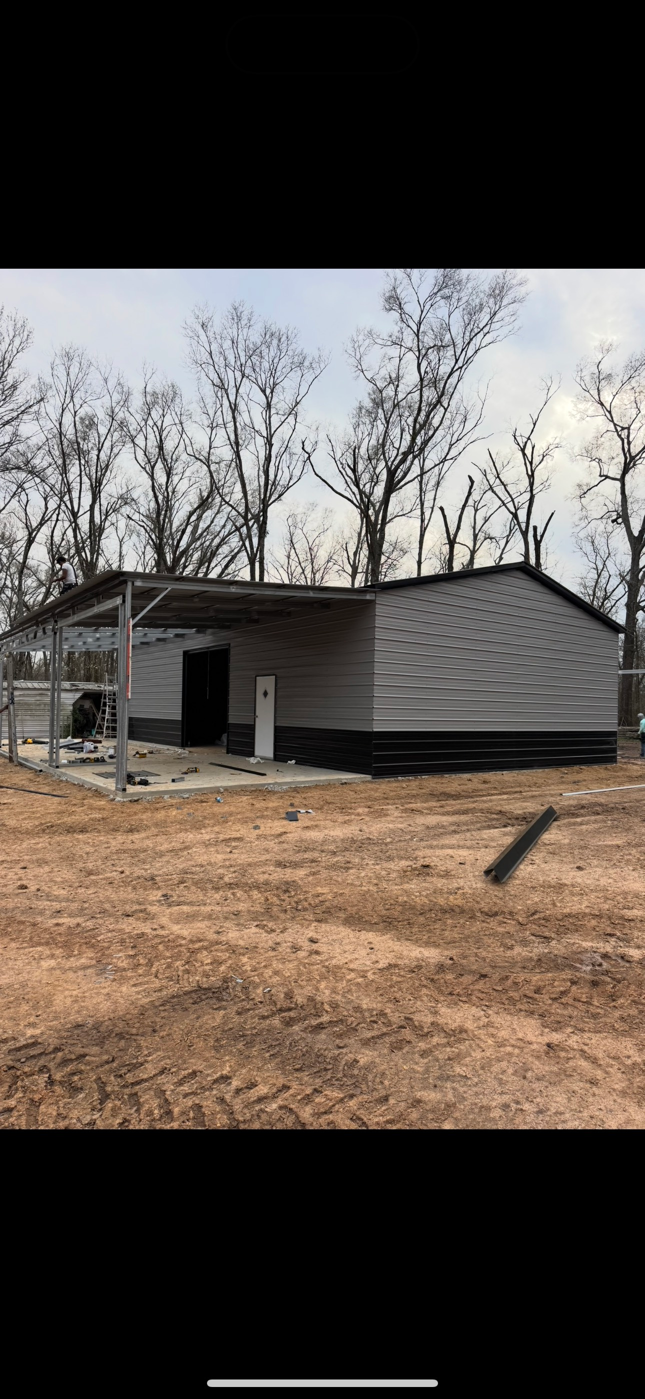 A large metal building is sitting in the middle of a dirt field.