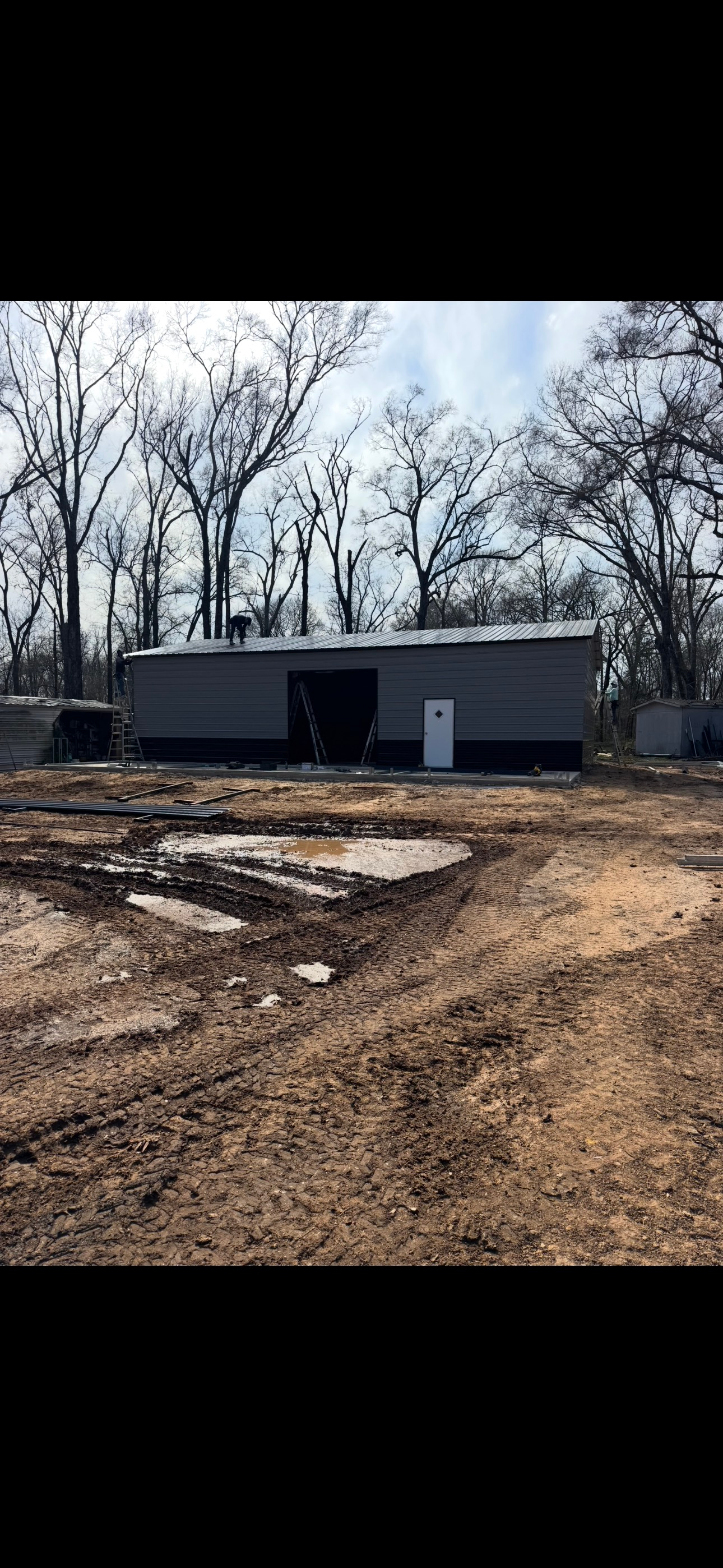 A large building is sitting in the middle of a dirt field.