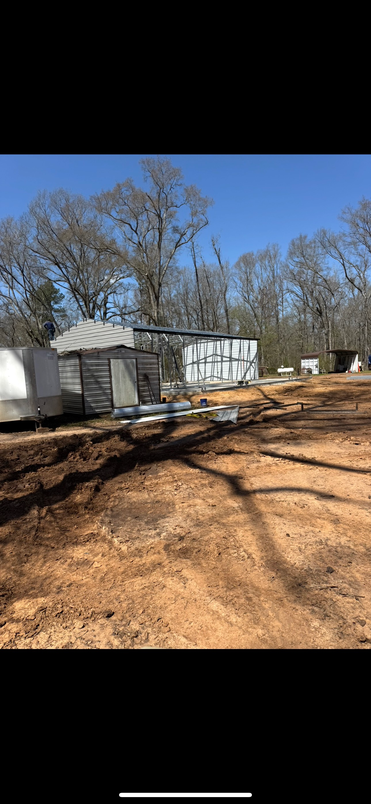 A trailer is sitting in the middle of a dirt field next to a house.