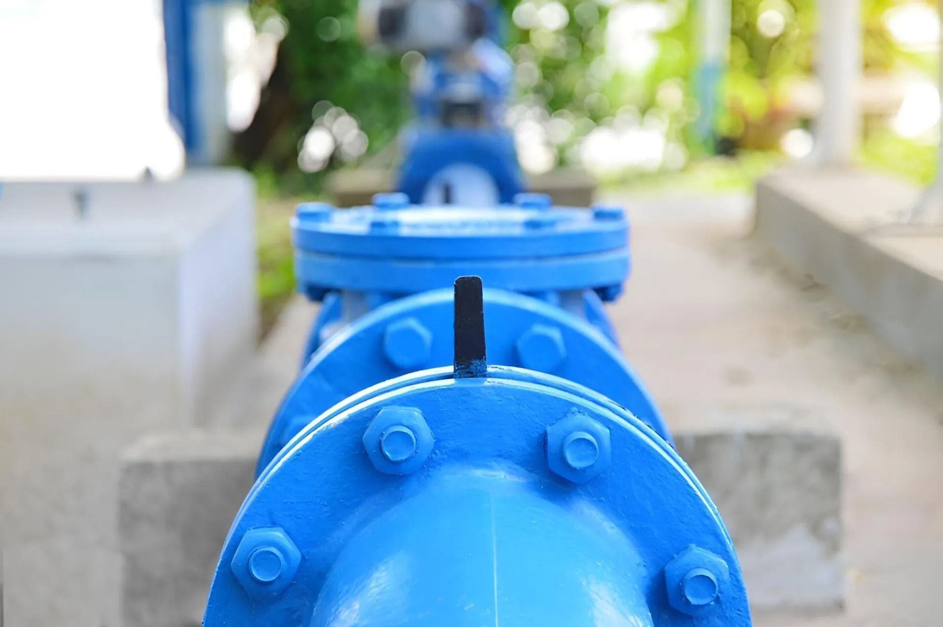 Blue water pipes with bolted flanges in an outdoor setting.