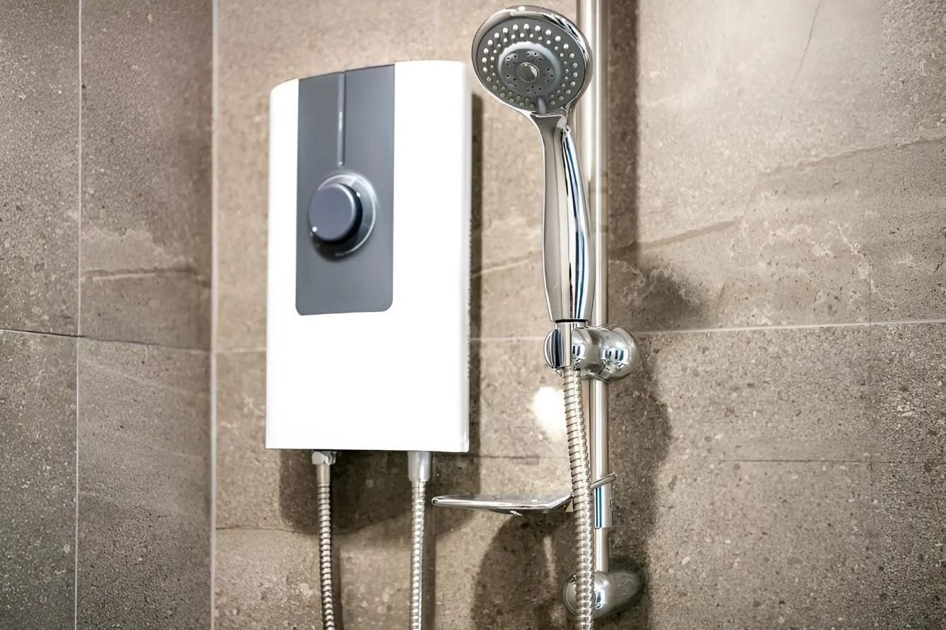 White electric shower unit with a gray control knob, next to a chrome shower head on a tiled wall.