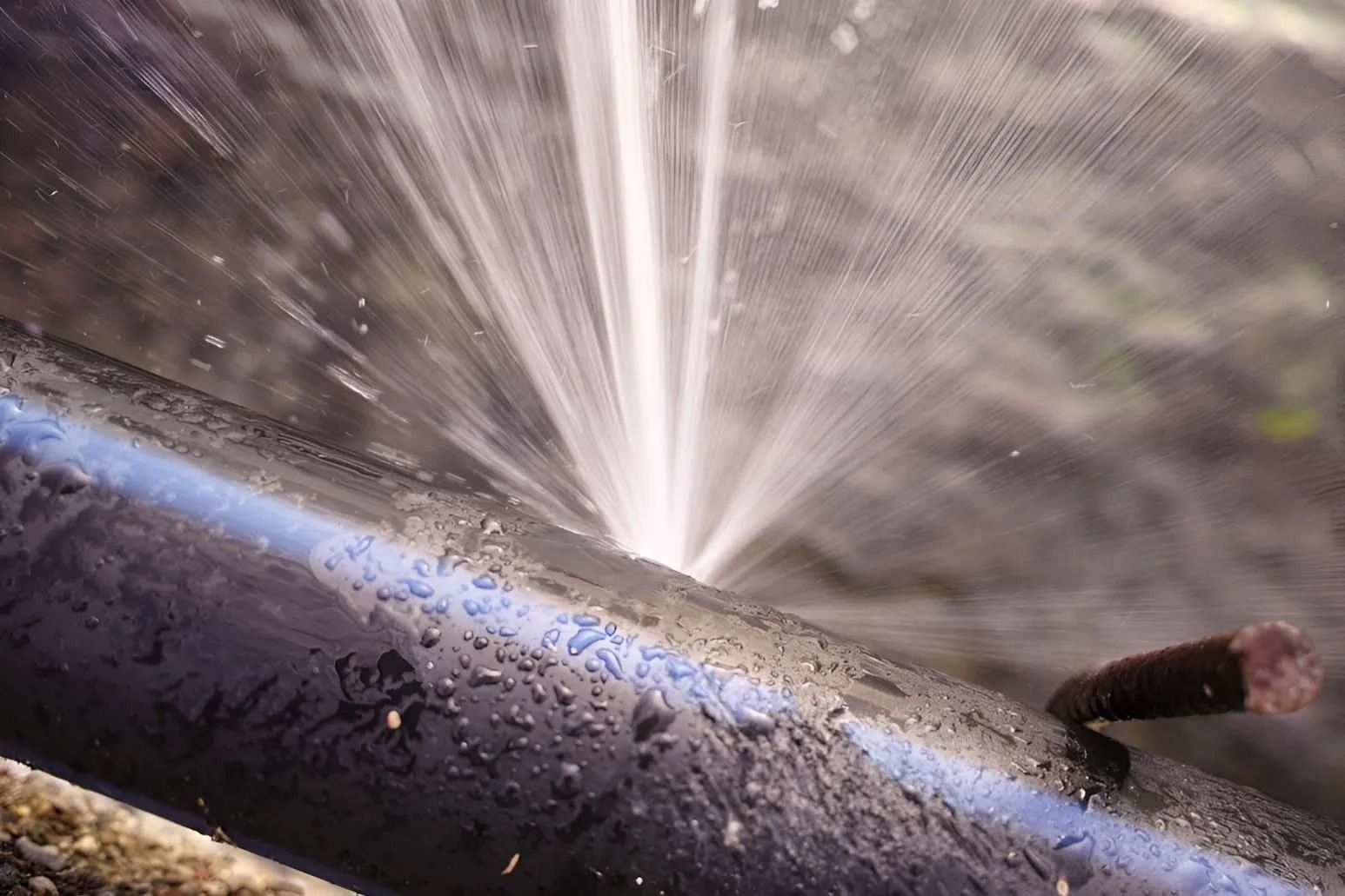 Black pipe spewing water, likely from a puncture or break.