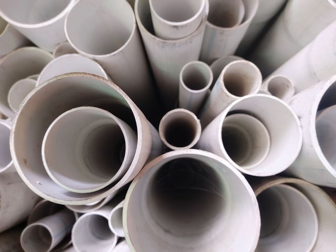 Pile of various sized white PVC pipes.