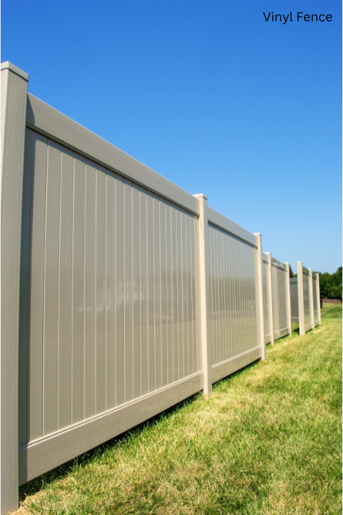 A vinyl fence is sitting in the middle of a lush green field.