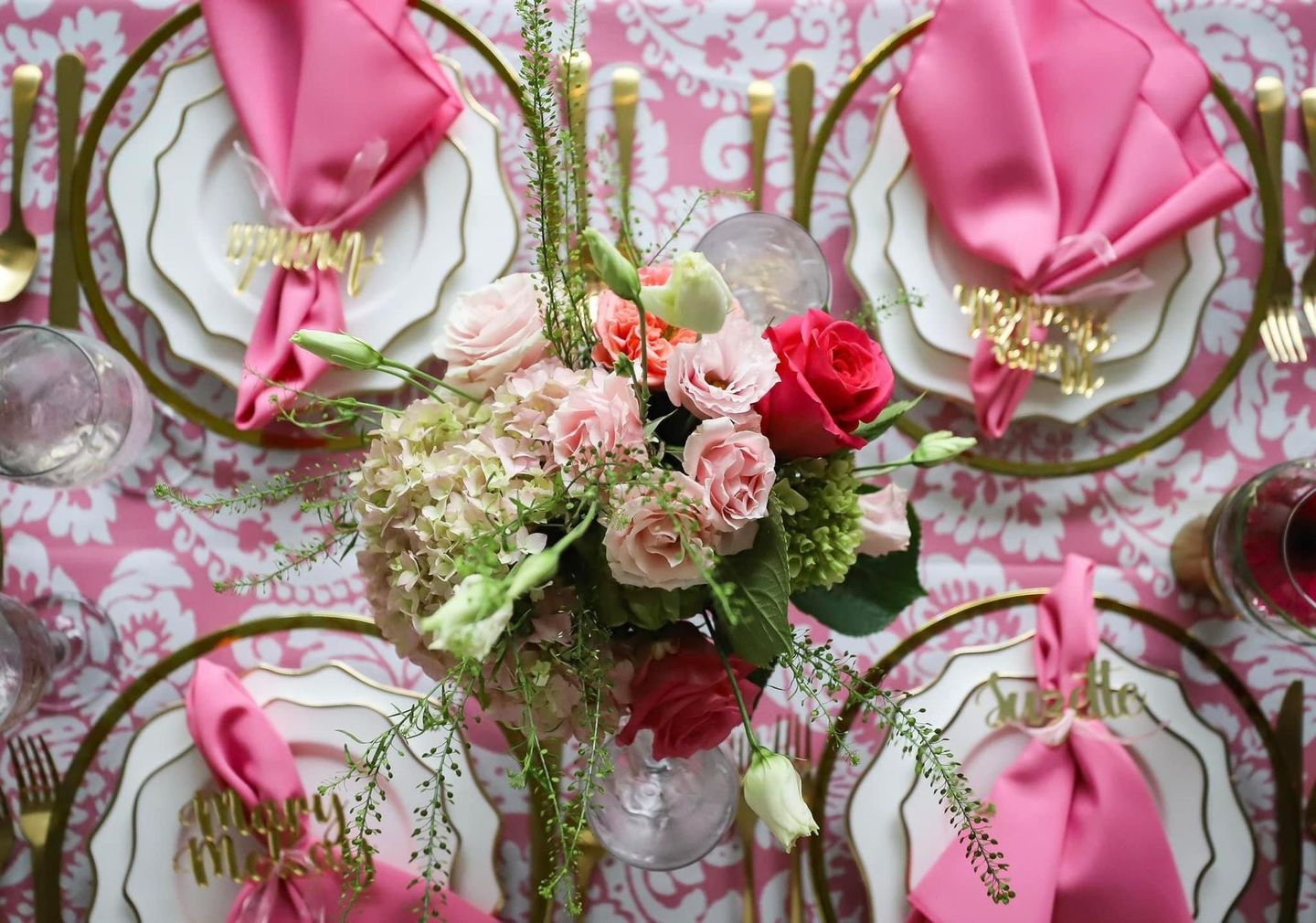 Pink floral table setting with gold accents and a central flower arrangement