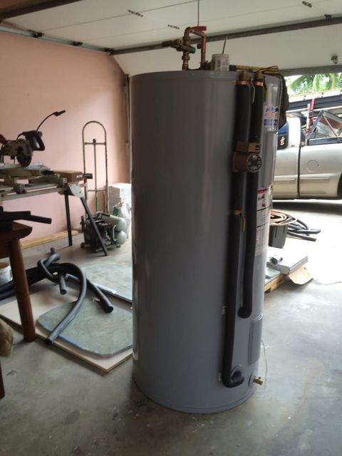 A large gray water heater is sitting in a garage