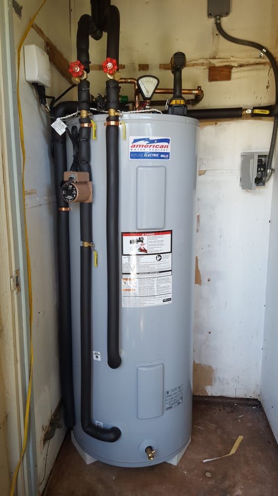 A water heater is sitting in a room next to a wall.