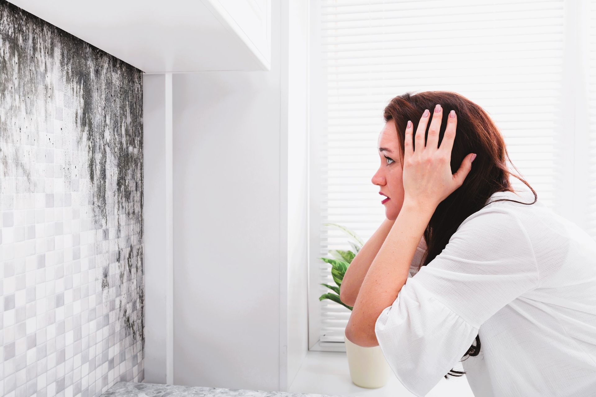 Young woman examining wall mold, unsure if it's black mold or mildew.