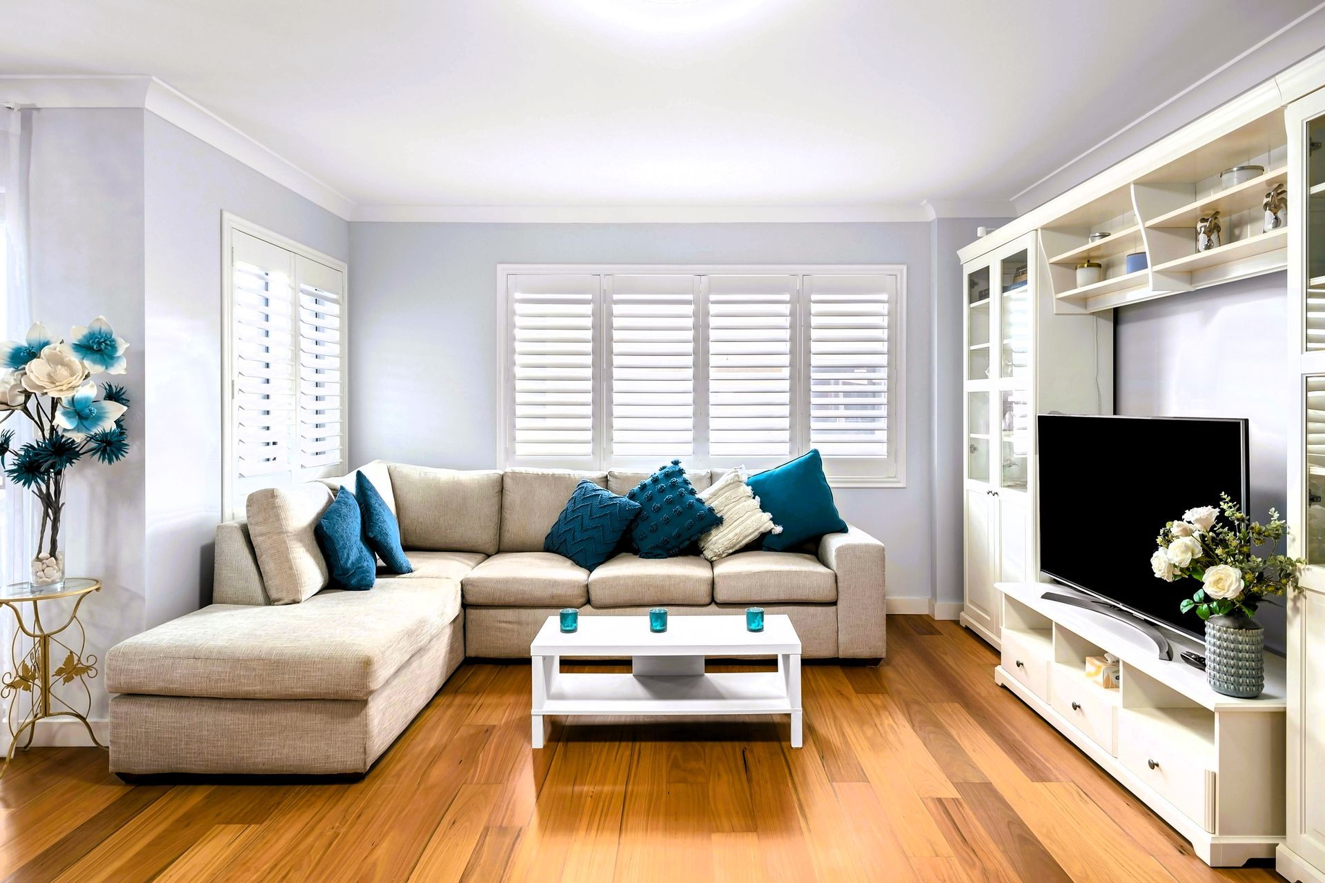 Modern living room with beige sectional sofa and blue cushion.