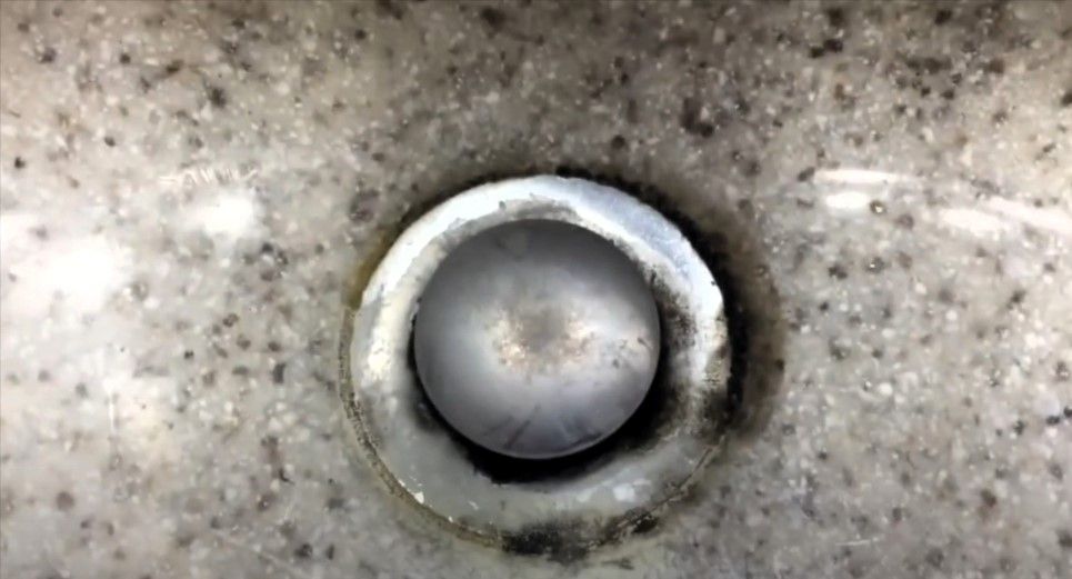 Close-up of a dirty sink drain with visible mold buildup.