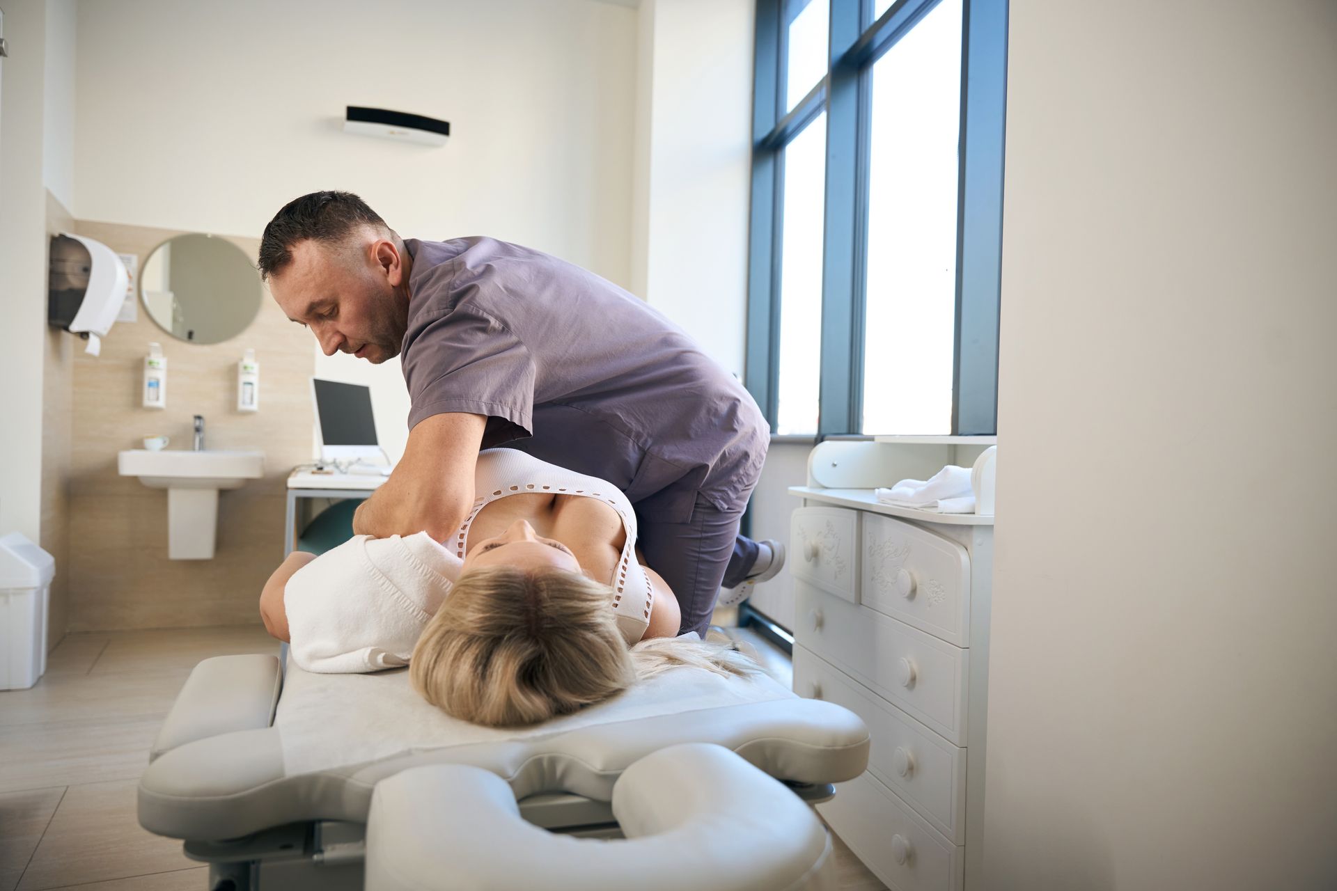 A chiropractor adjusting a woman who is laying on her back.