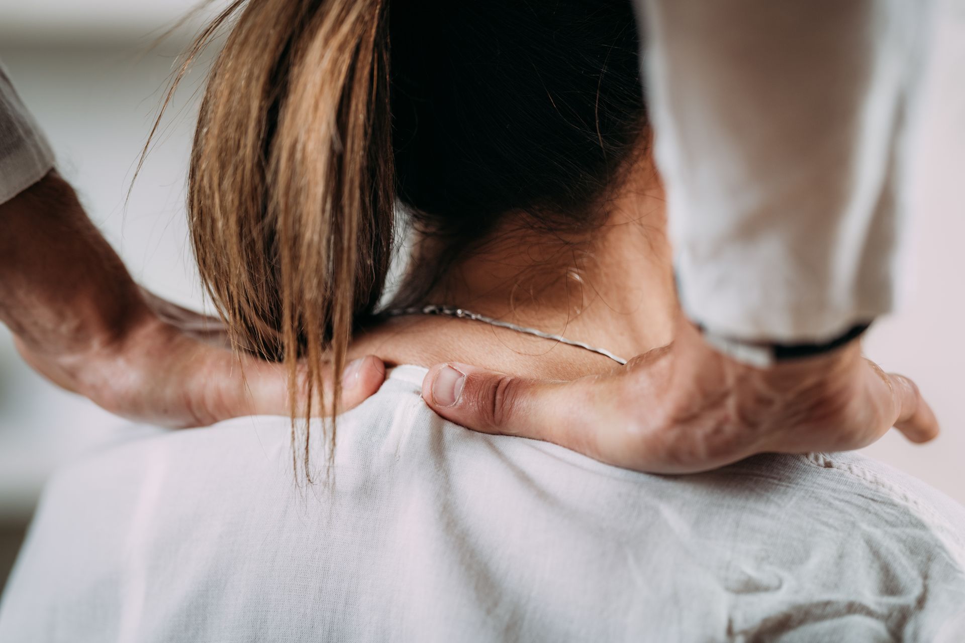 Person receiving a neck adjustment from a chiropractor's hands.