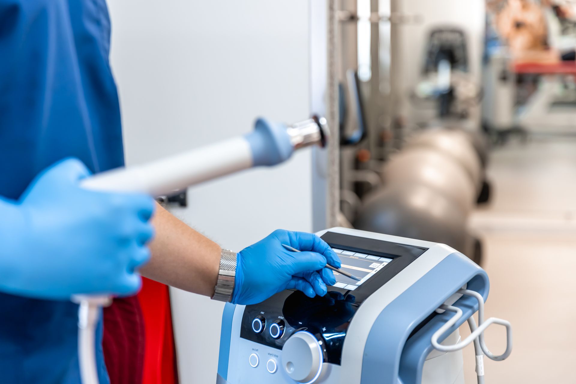 Medical professional adjusting a shockwave therapy machine in a clinic, holding the applicator.