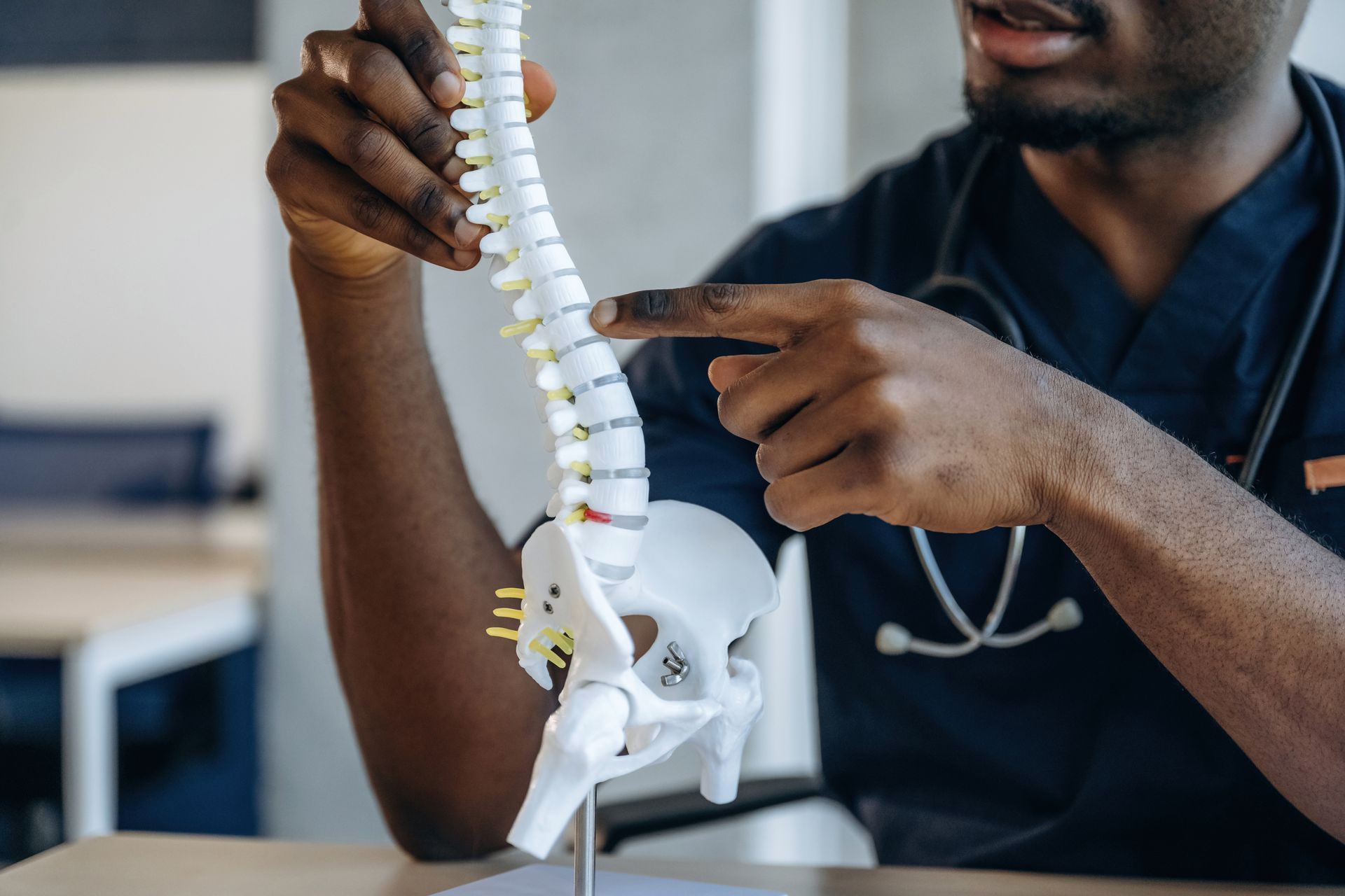 Doctor points to a model spine, explaining the anatomy.