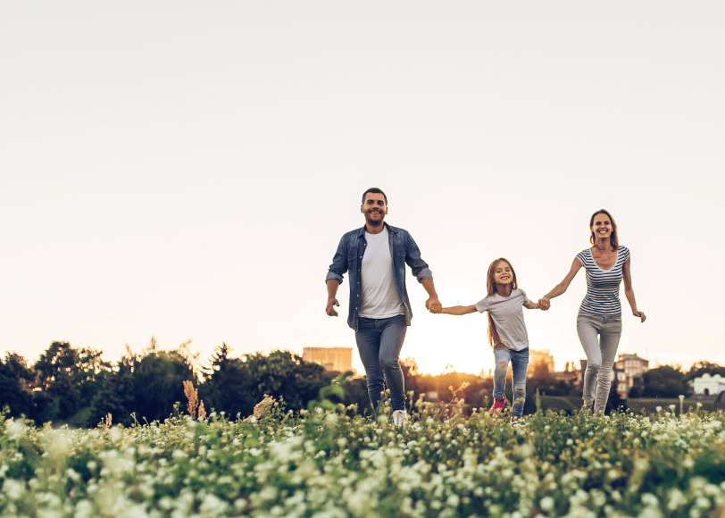 A family is walking through a field of flowers holding hands.