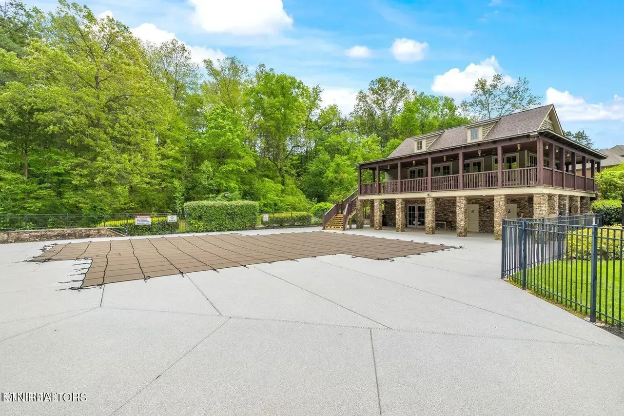 Covered swimming pool with a stone-based building and trees in the background.