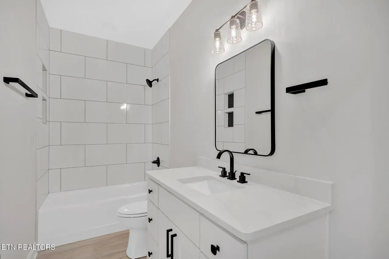 White bathroom with a white vanity, black fixtures, and a large mirror.