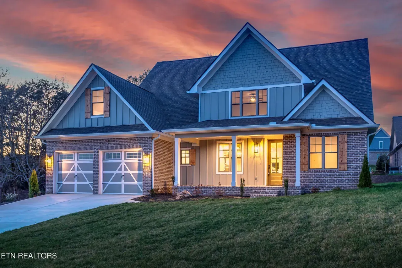 House exterior with blue siding, two-car garage, porch, and dusk sky.