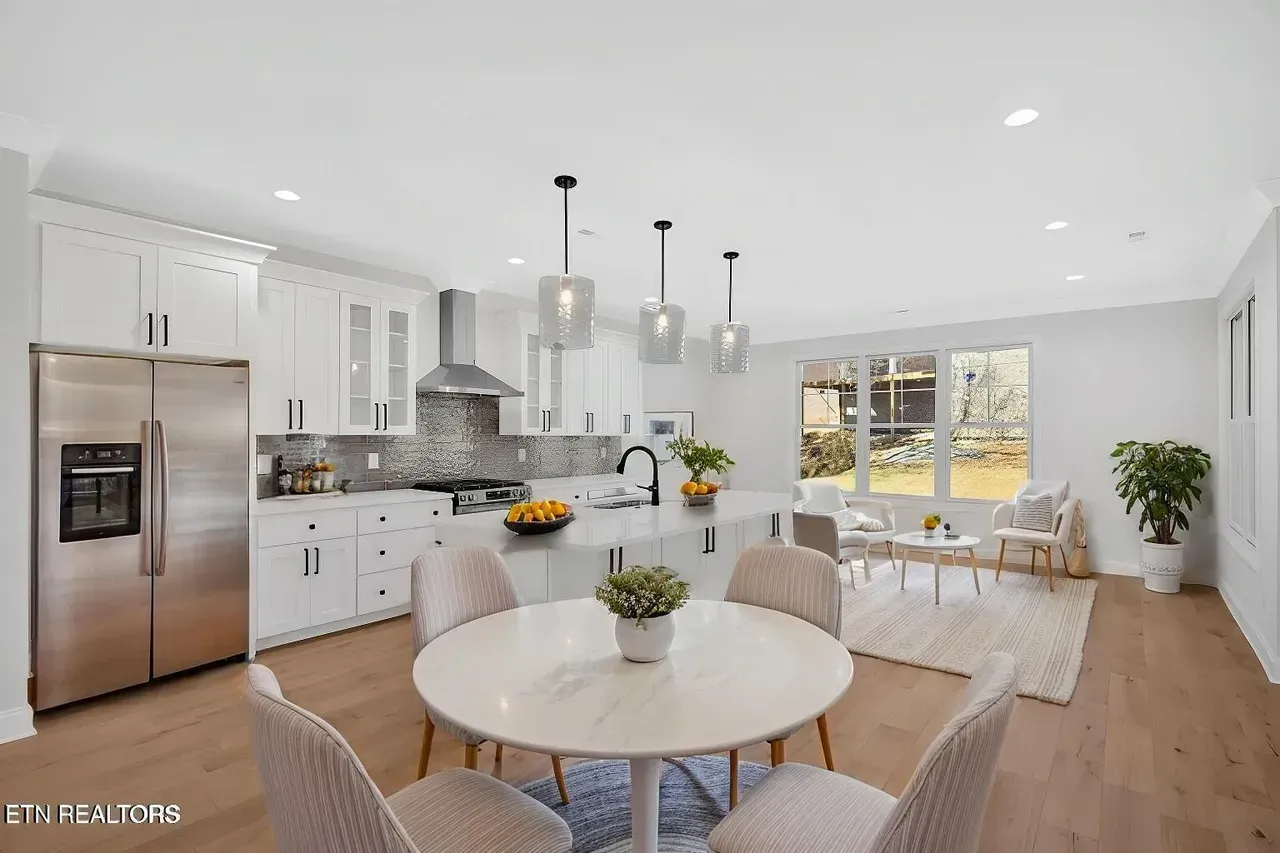 Bright, modern kitchen with white cabinets, stainless steel appliances, and a dining table.