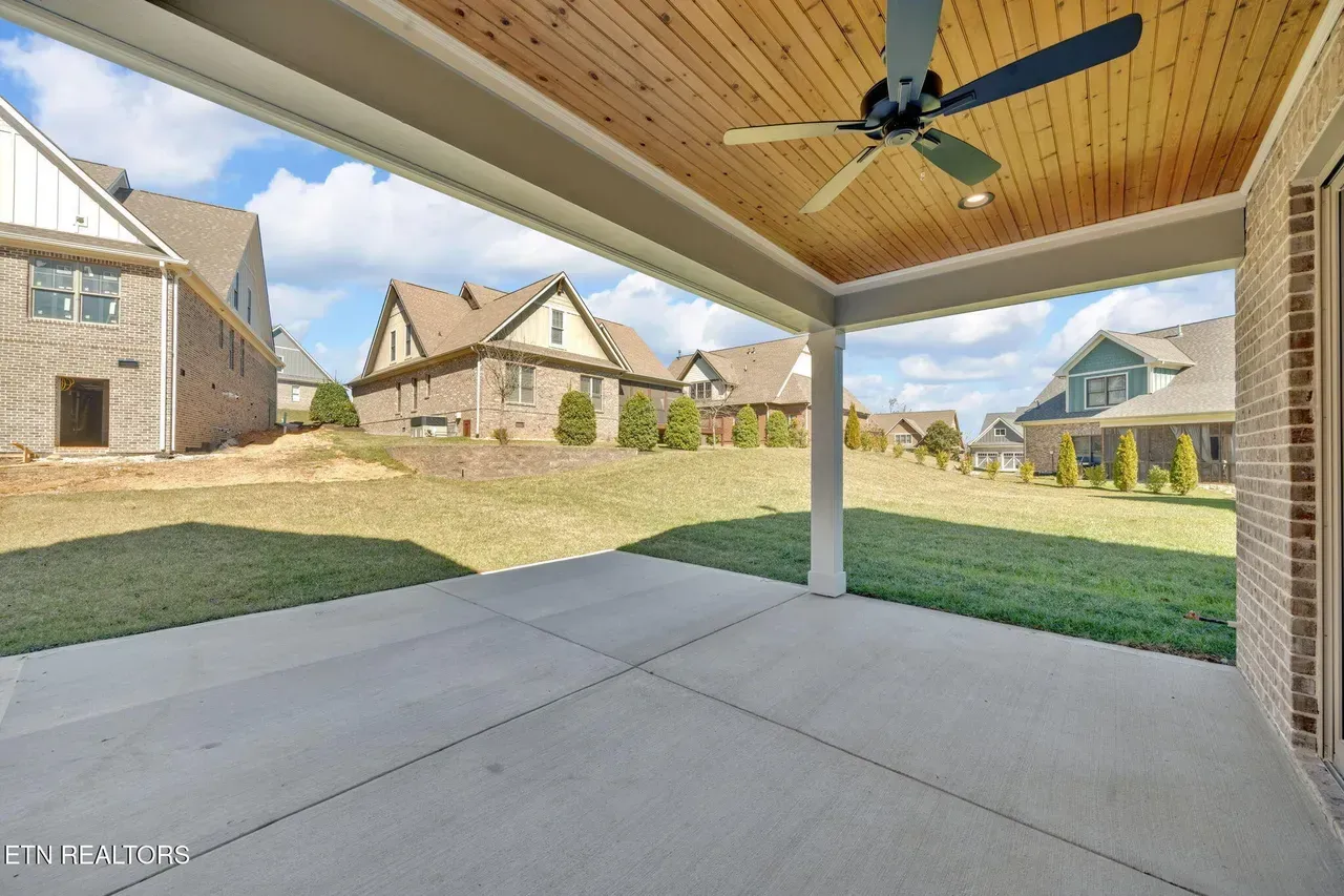 Covered patio with a concrete floor, wooden ceiling, ceiling fan, and view of houses.