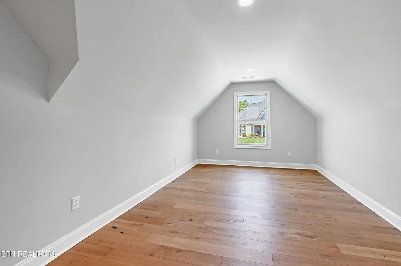 Empty attic room with wood floor and a small window.