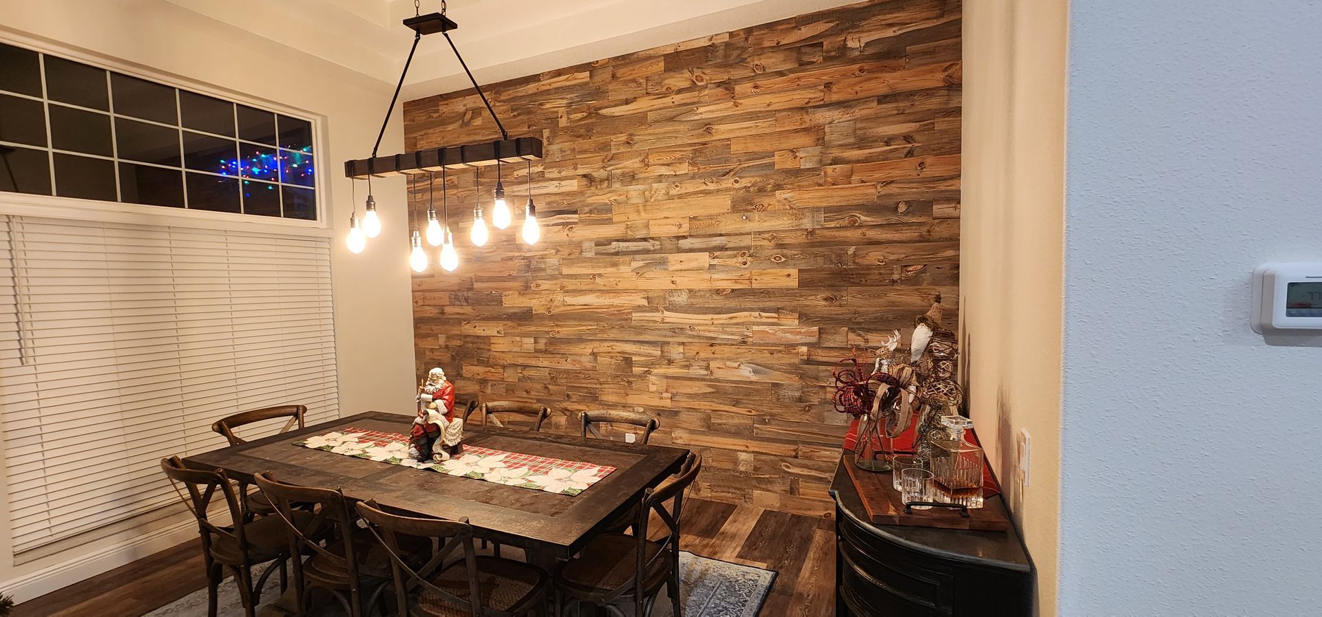 Dining room with a dark wooden table, brick wall, and a hanging light fixture.
