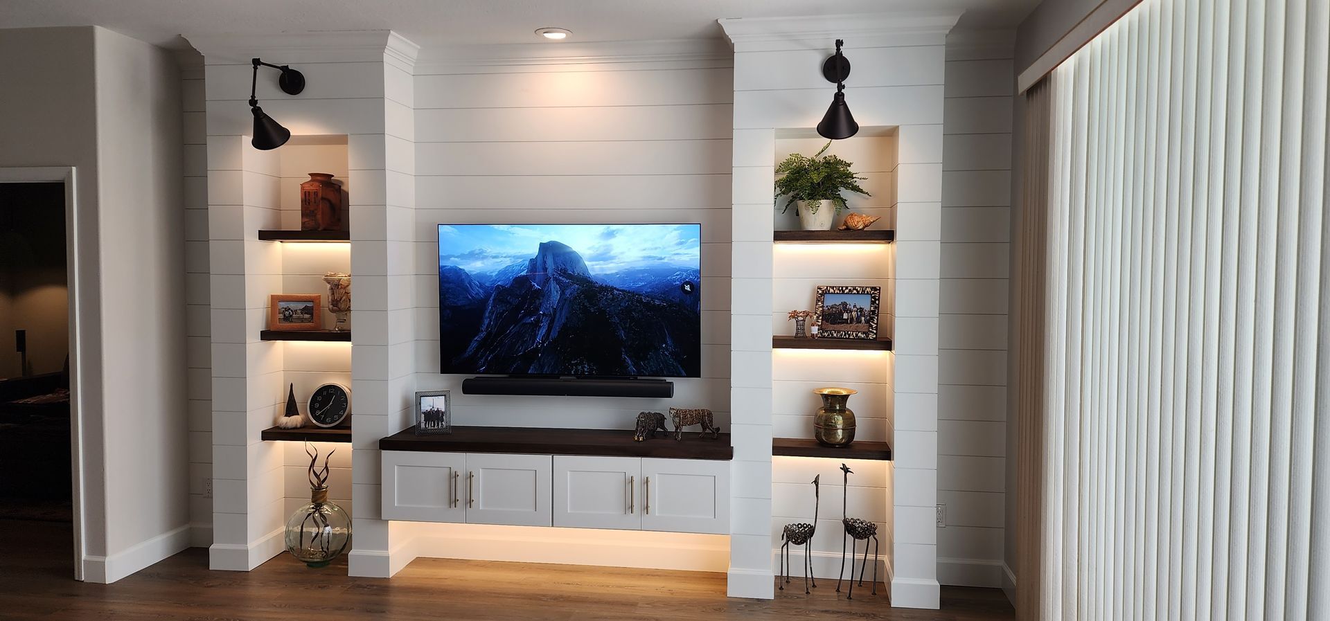 Living room with a built-in entertainment center with a TV, shelves, and cabinets.
