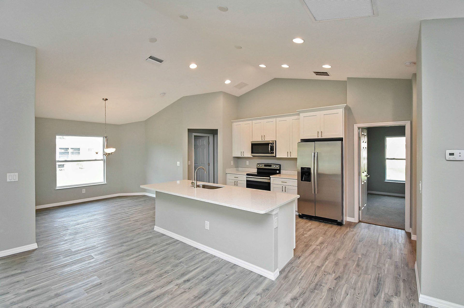 Modern kitchen with island, stainless steel appliances, and hardwood floors; neutral tones.