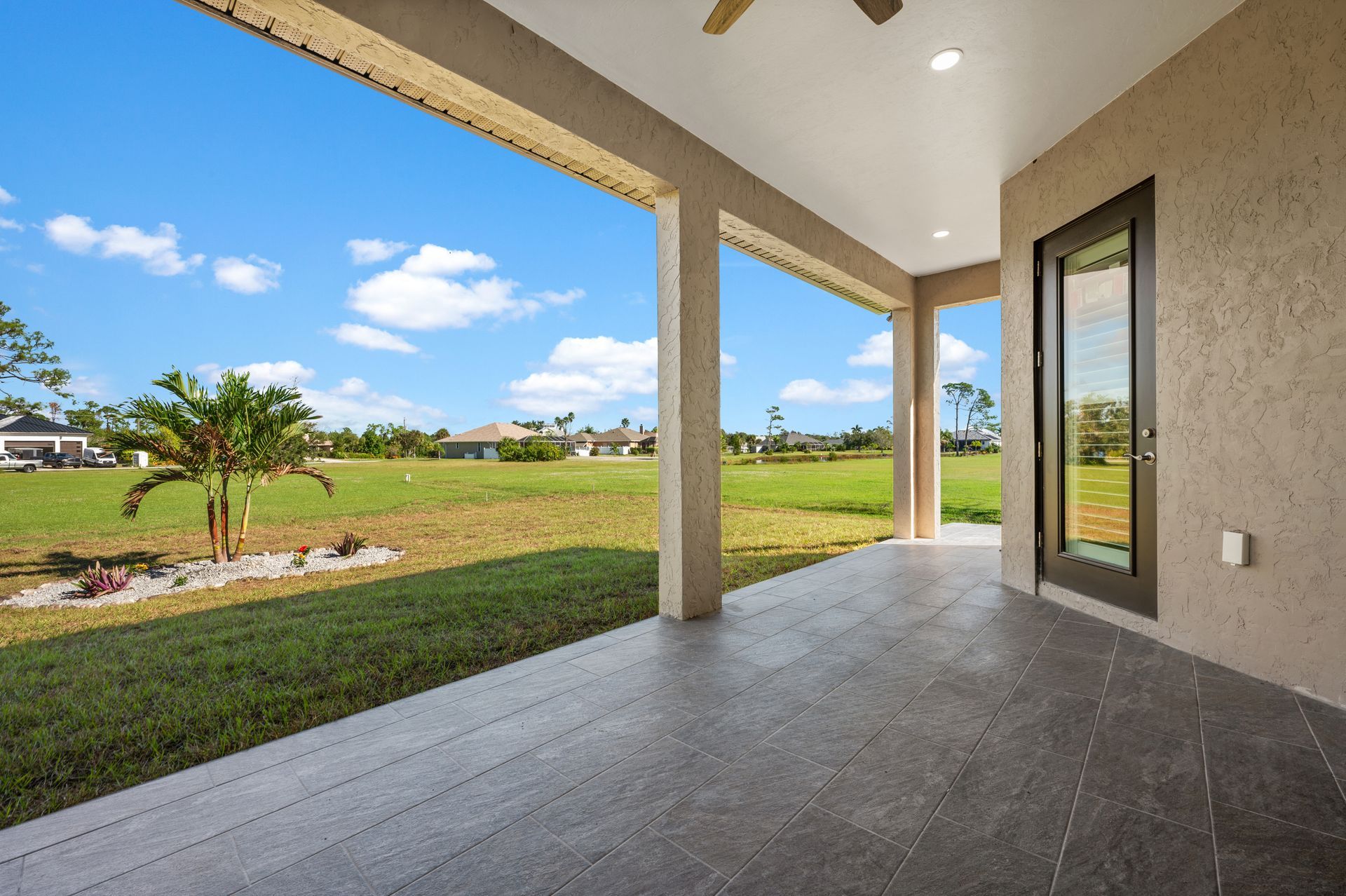 Covered patio with view of grassy yard and blue sky.
