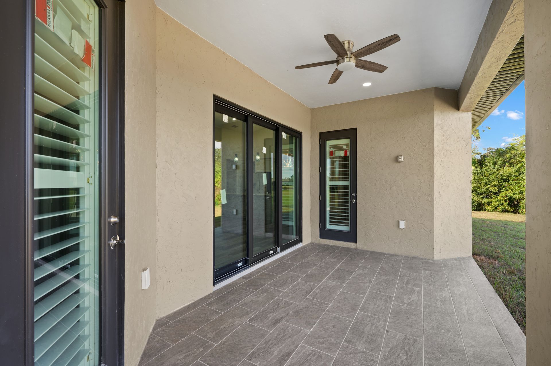 Covered patio with dark trim, sliding glass doors, and a ceiling fan.