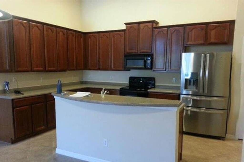 Kitchen with dark wood cabinets, stainless steel fridge, and light countertops.
