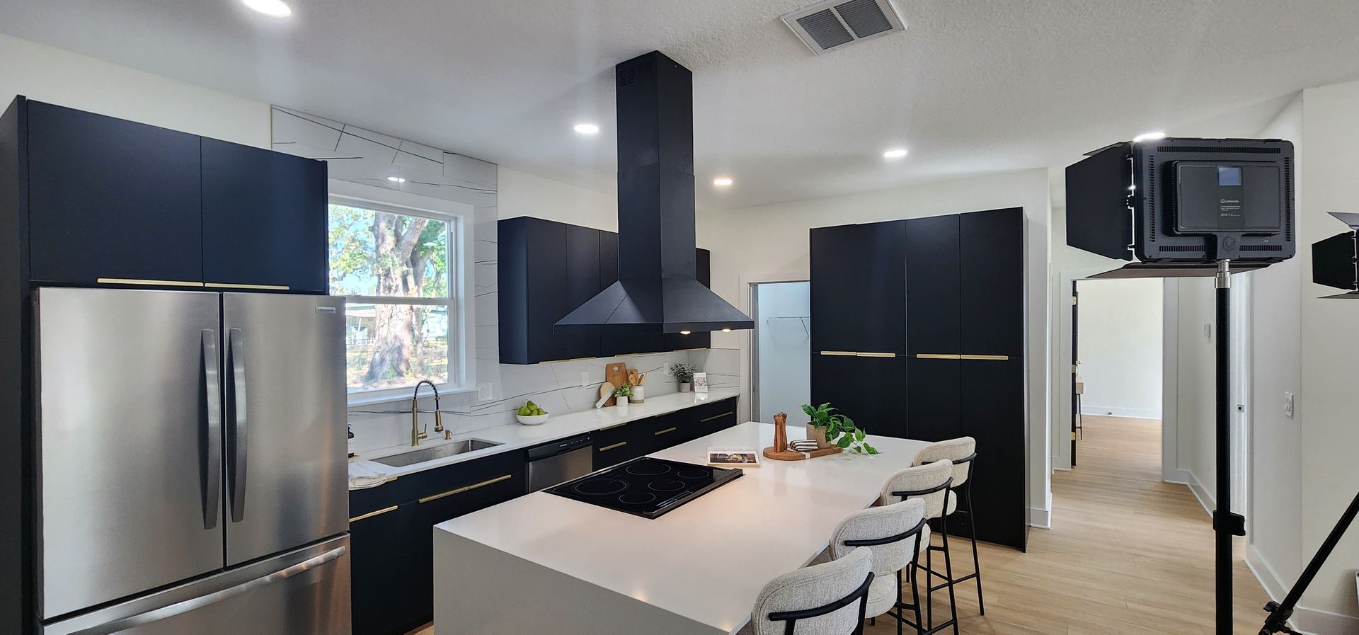 Modern kitchen with black cabinets, stainless steel appliances, and white island.