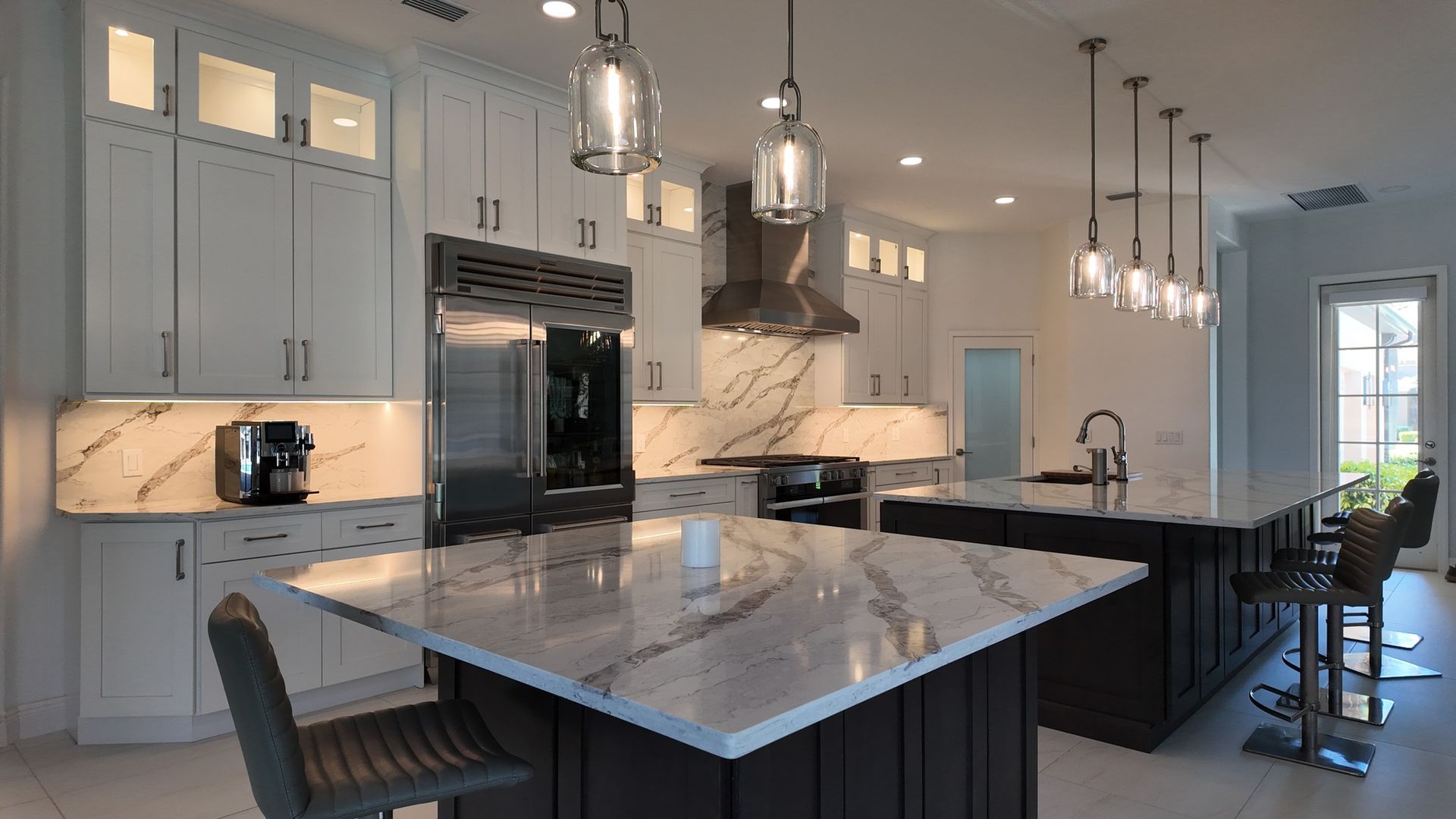 Modern kitchen with marble countertops, stainless steel appliances, and pendant lights.