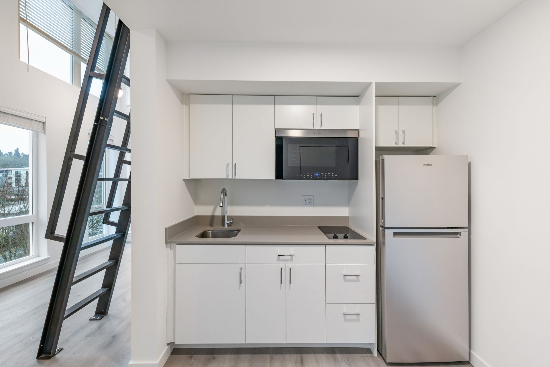 Small kitchen with white cabinets, stainless steel fridge, and gray countertop.