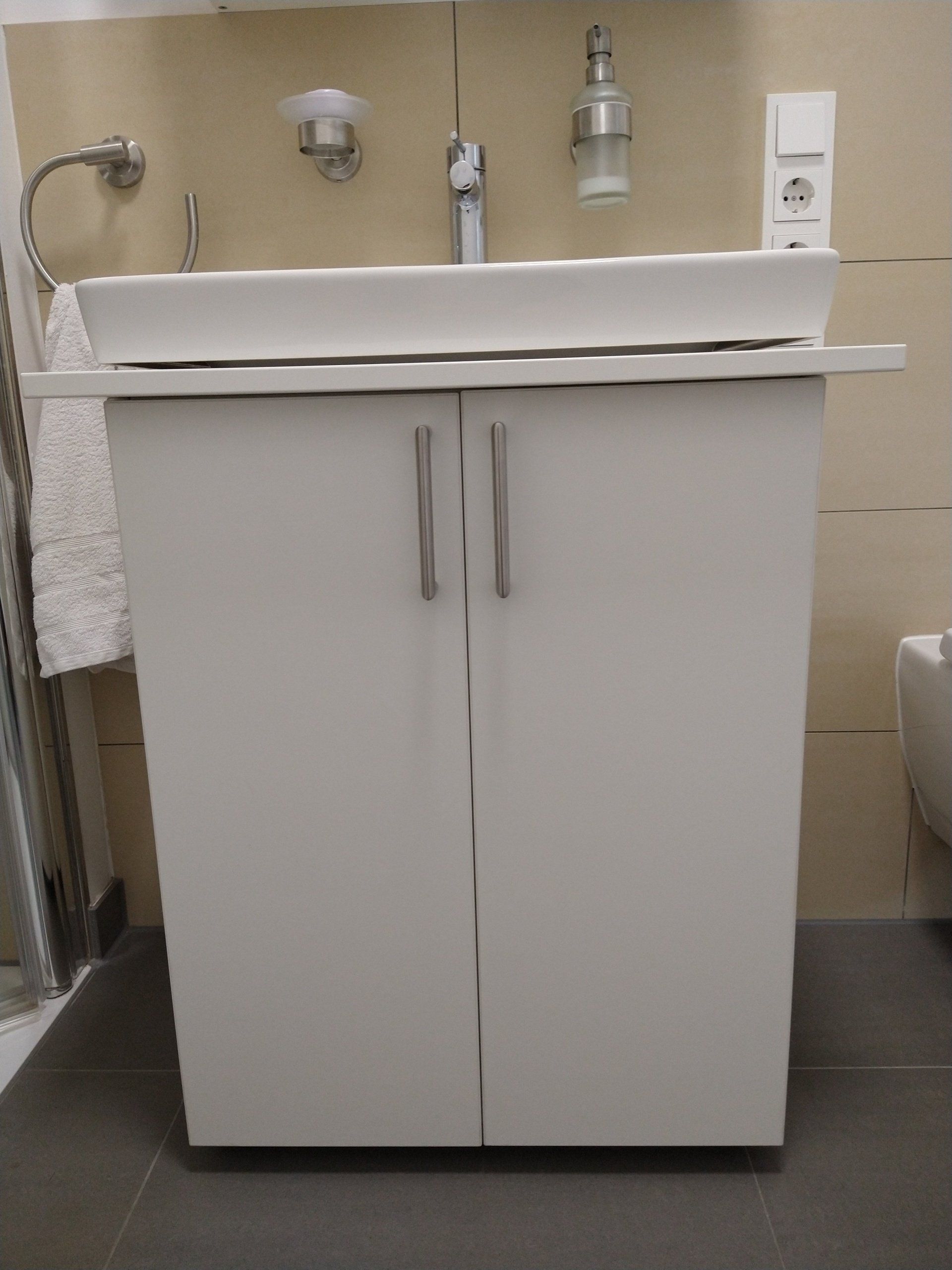 Ein Badezimmer mit einem weißen Waschbecken und einem weißen Schrank