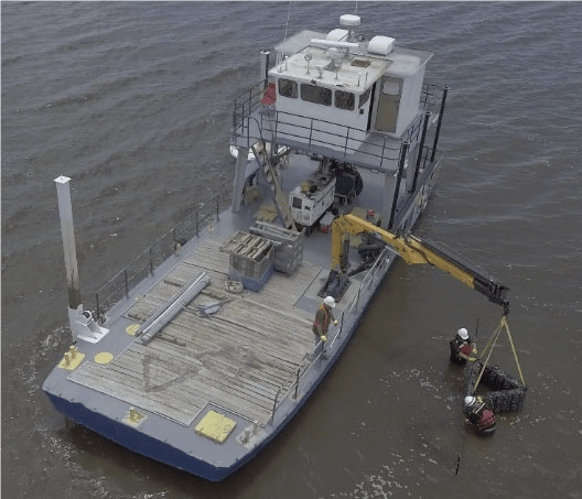A boat with a crane on it is in the water - Baton Rouge, LA - Coastal Environments, Inc.