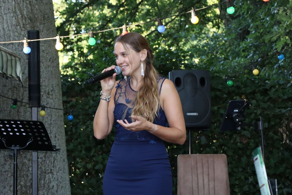 A woman in a blue dress is singing into a microphone.