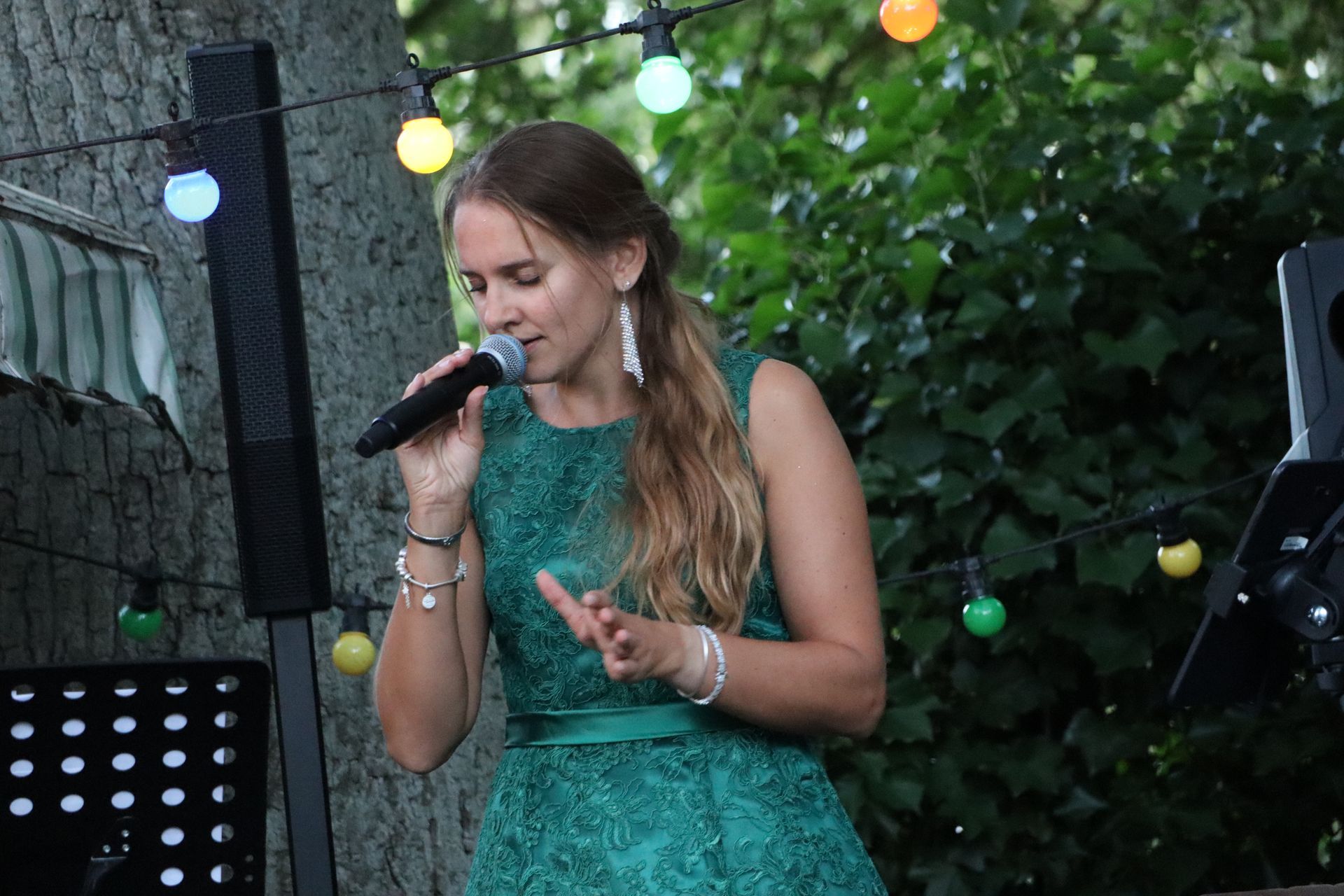 A woman in a green dress is singing into a microphone.