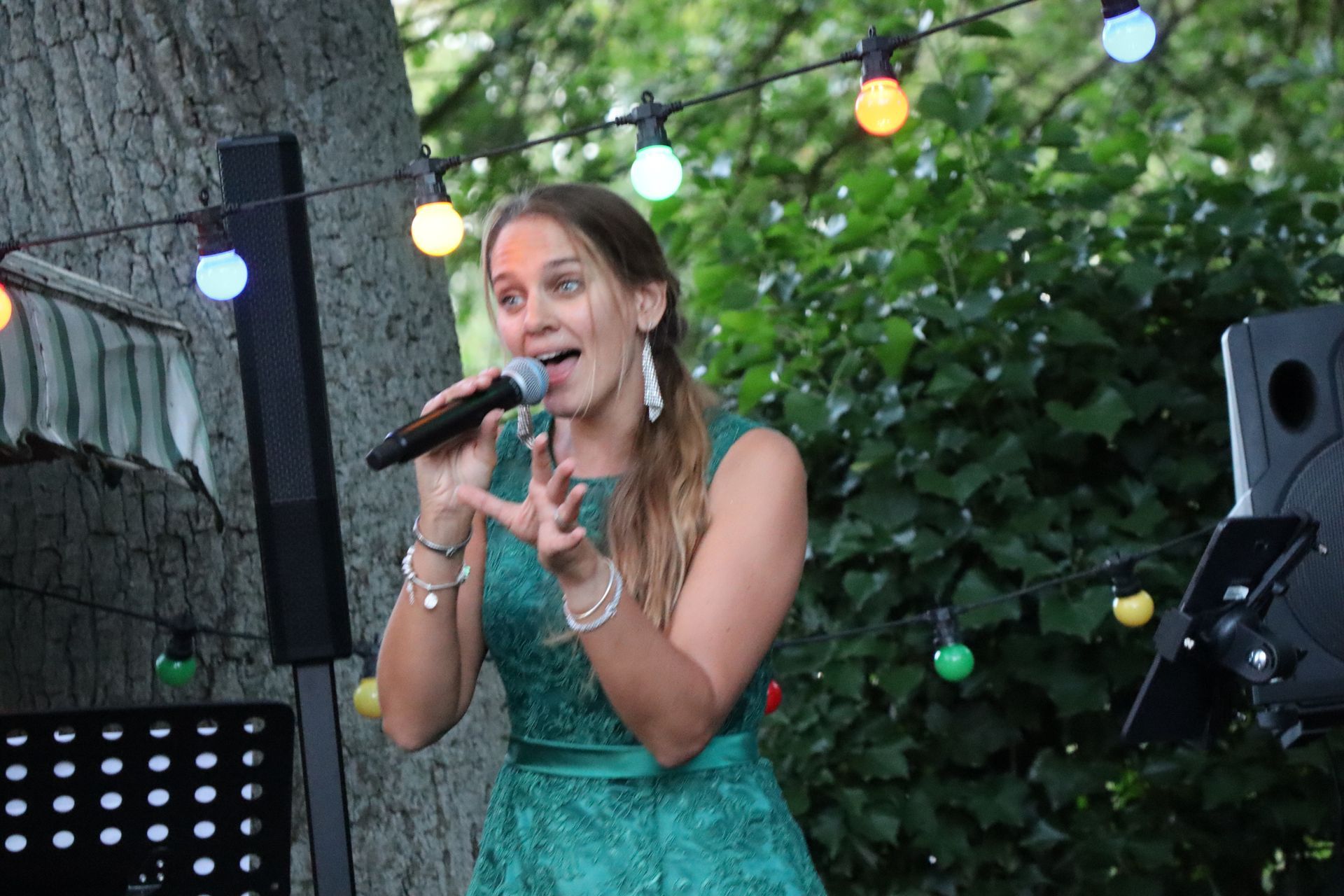 A woman in a green dress is singing into a microphone.