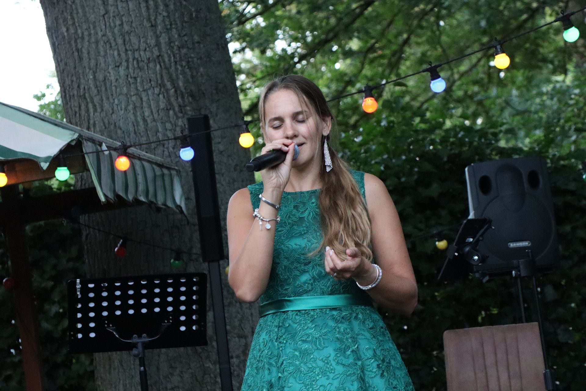 A woman in a green dress is singing into a microphone.