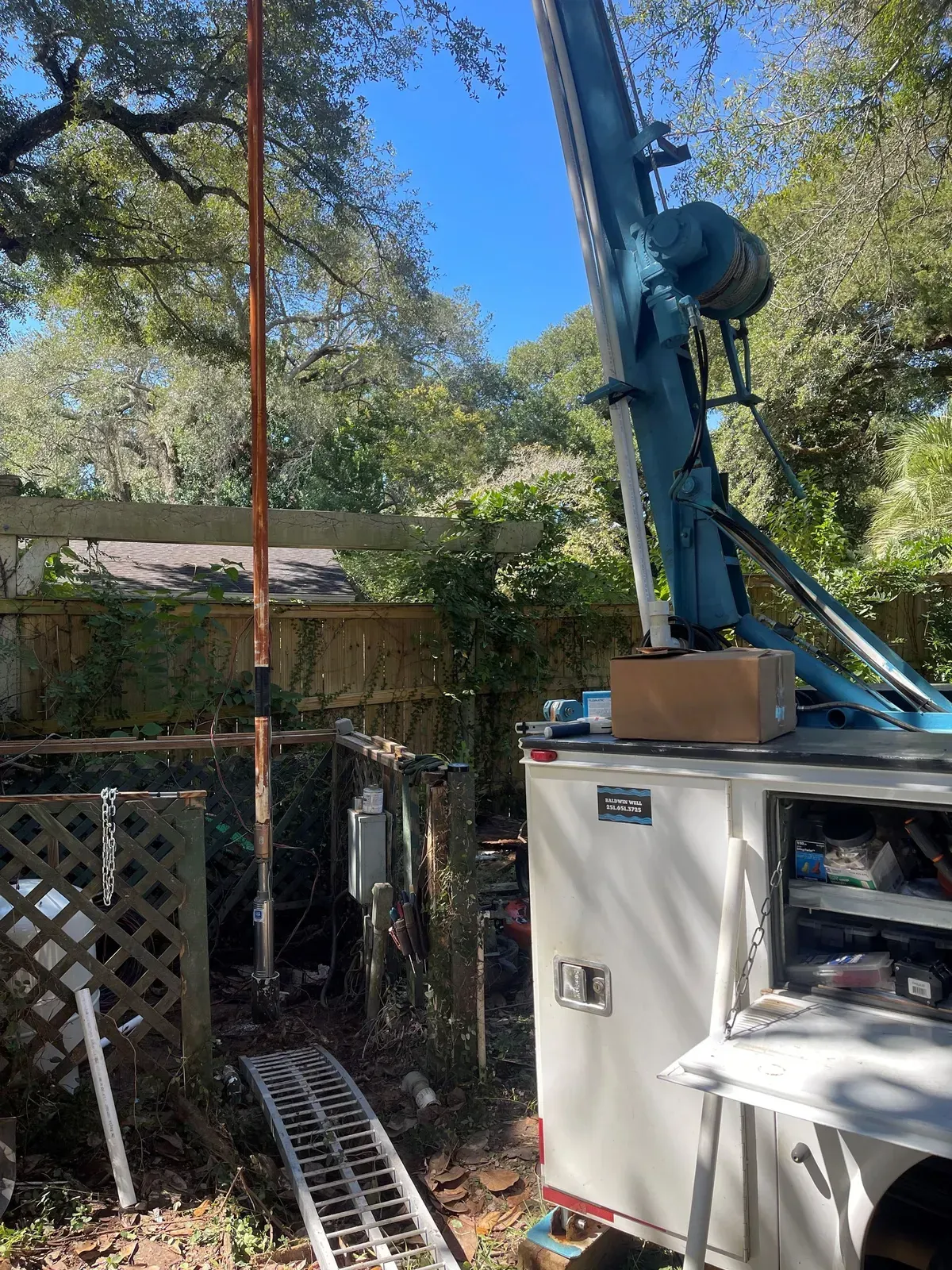 A crane is sitting on top of a white truck in a backyard.